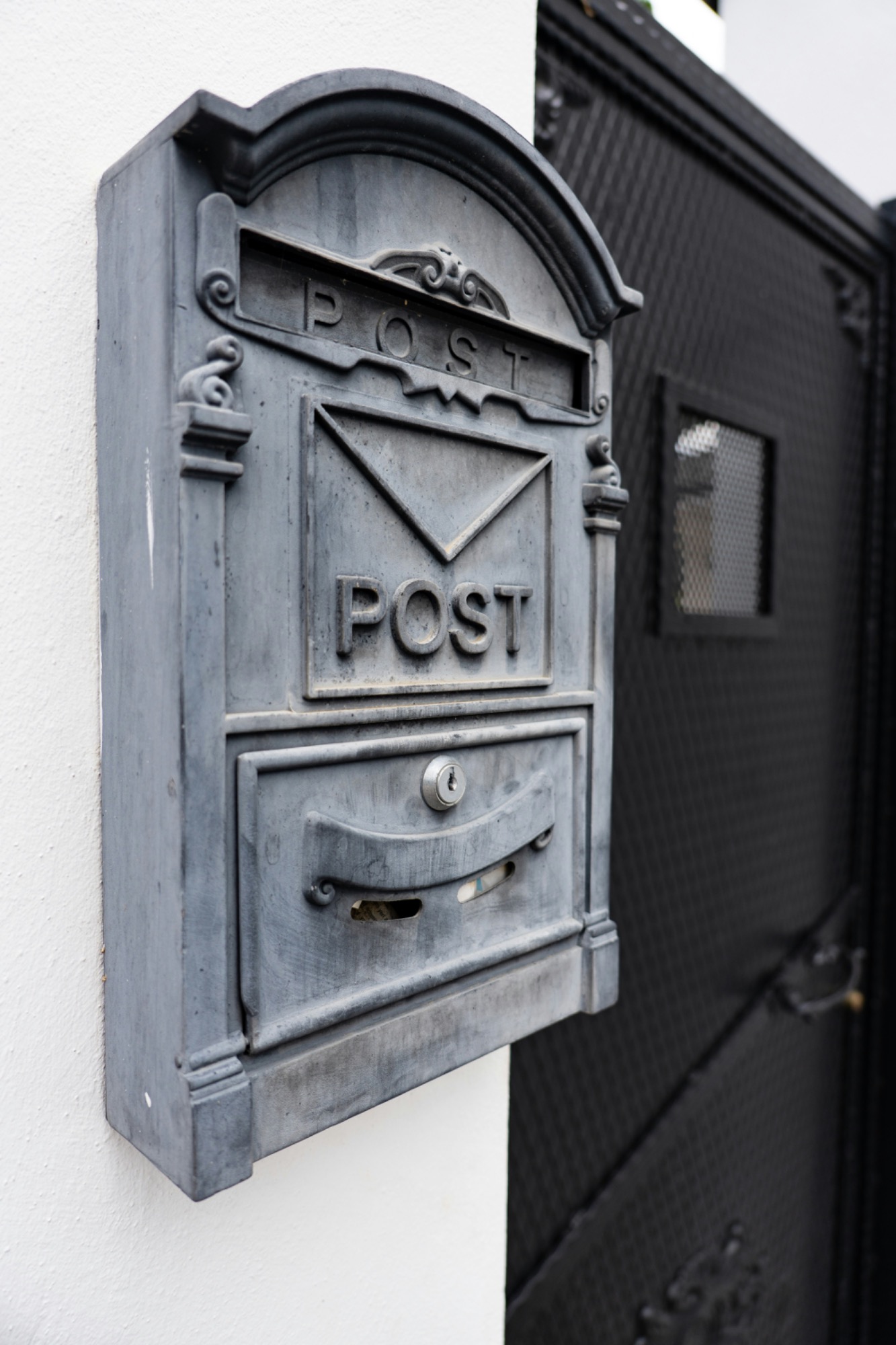 Briefkastenleerung Graue Briefkasten mit der Aufschrift "POST" an einer Wand montiert.