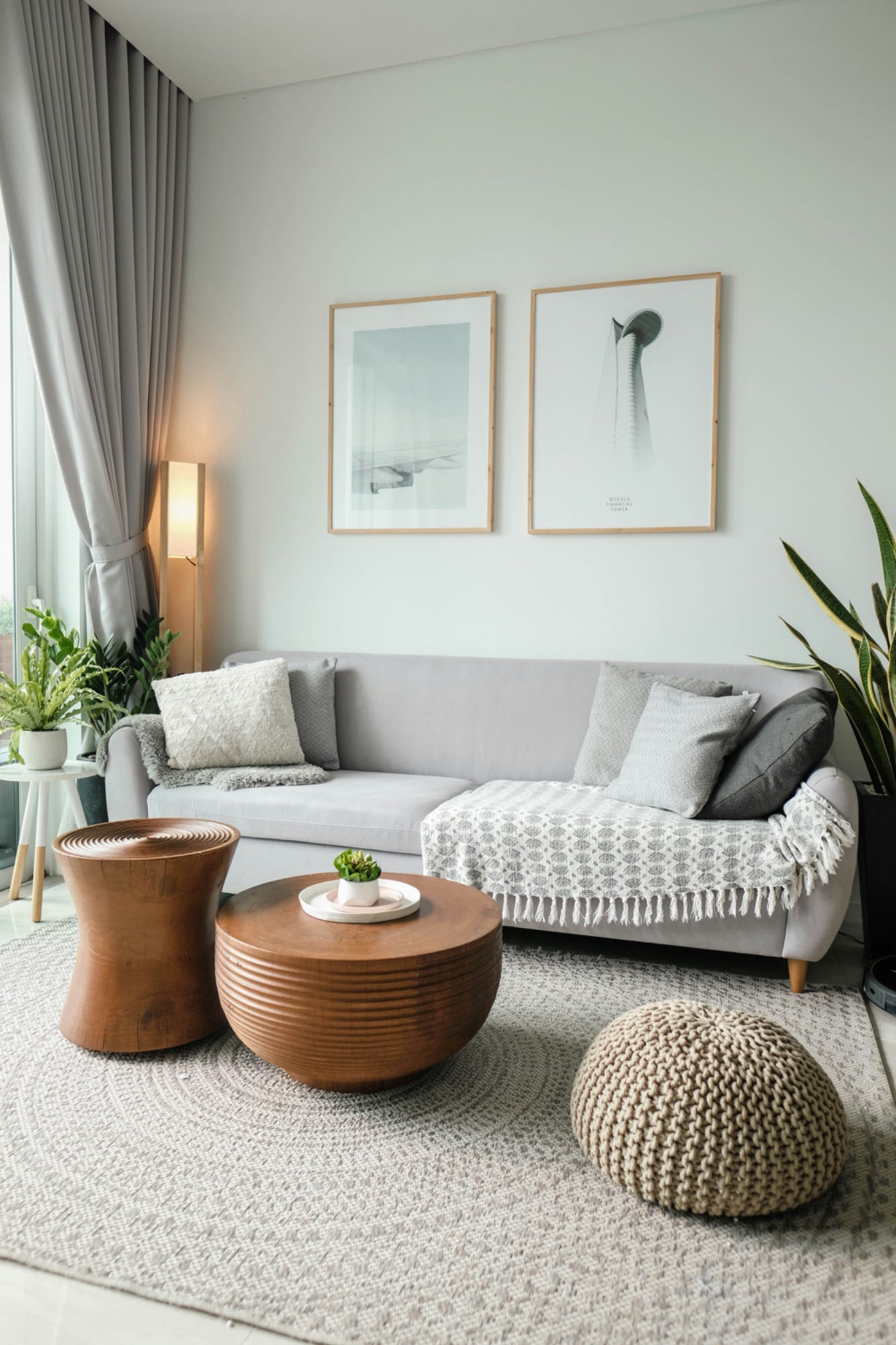 sauberes Wohnzimmer Helles Wohnzimmer mit grauem Sofa, runden Holztischen und modernen Pflanzen.