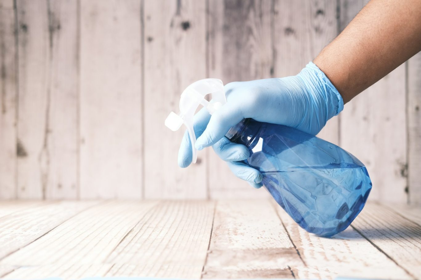 Sprühflasche Eine Hand in blauen Handschuhen hält eine Sprühflasche mit blauer Flüssigkeit.
