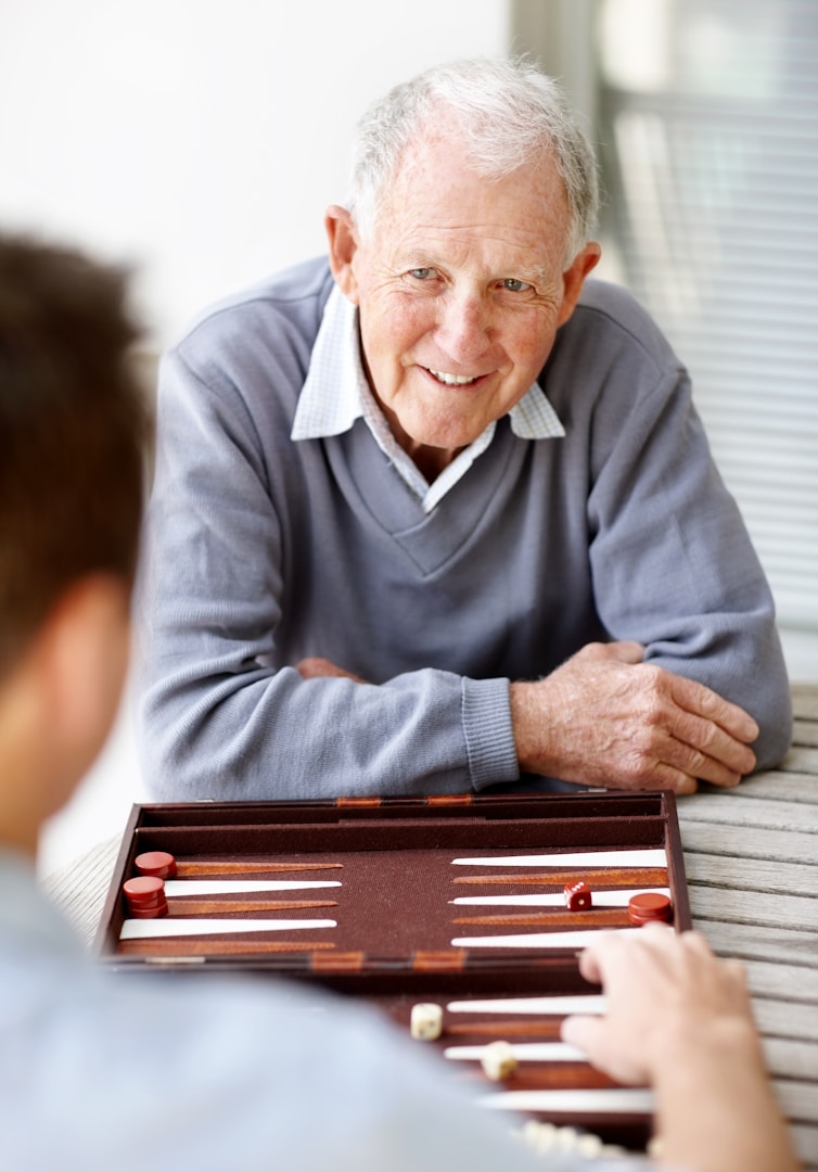 Unterhaltung Älterer Mann spielt Backgammon mit einem jüngeren Mitspieler. Freundliche Atmosphäre.