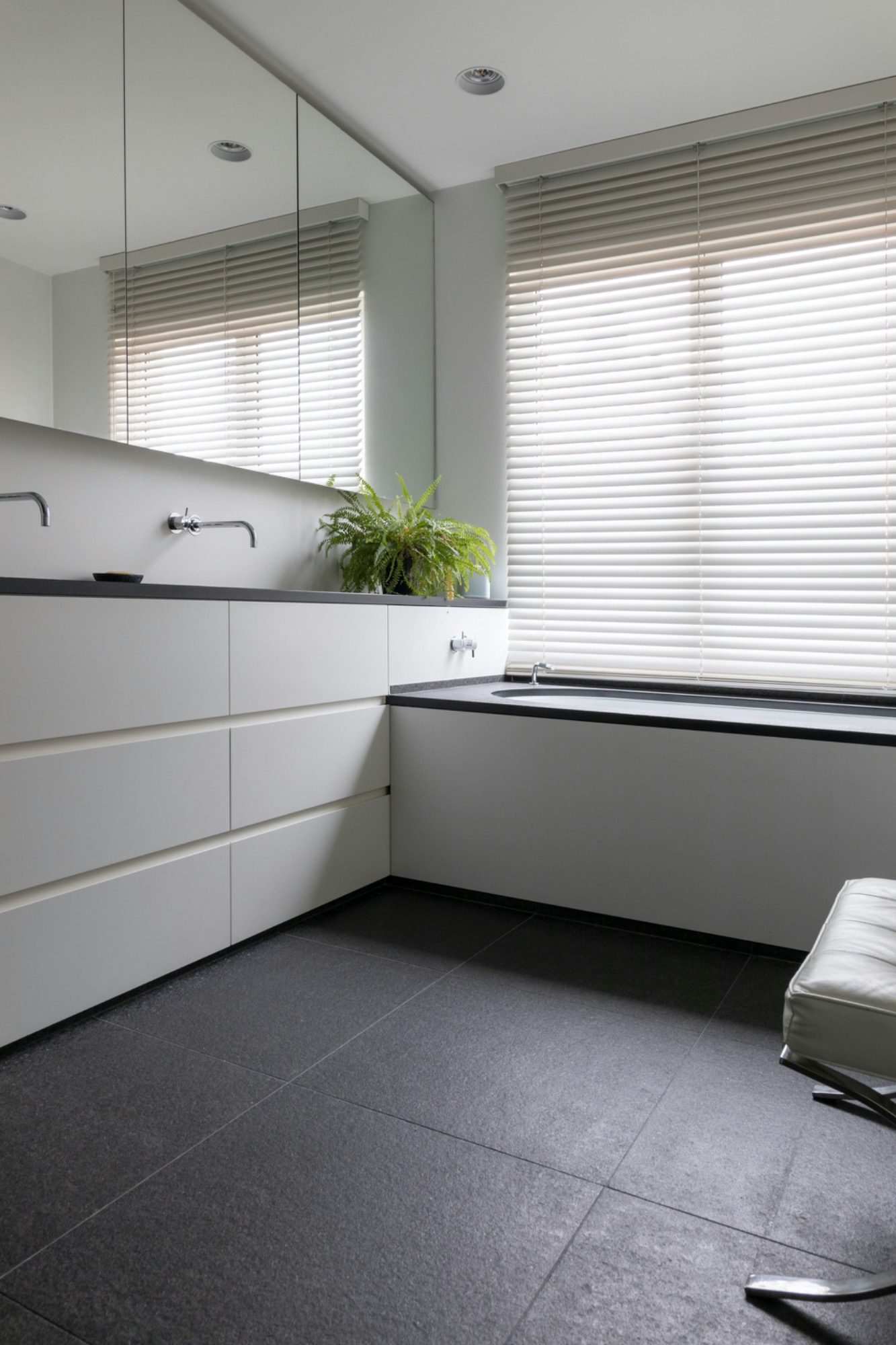 Sauberes Badezimmer Modern Badezimmer mit weißen Möbeln, großem Spiegel und Fenster mit Jalousien.