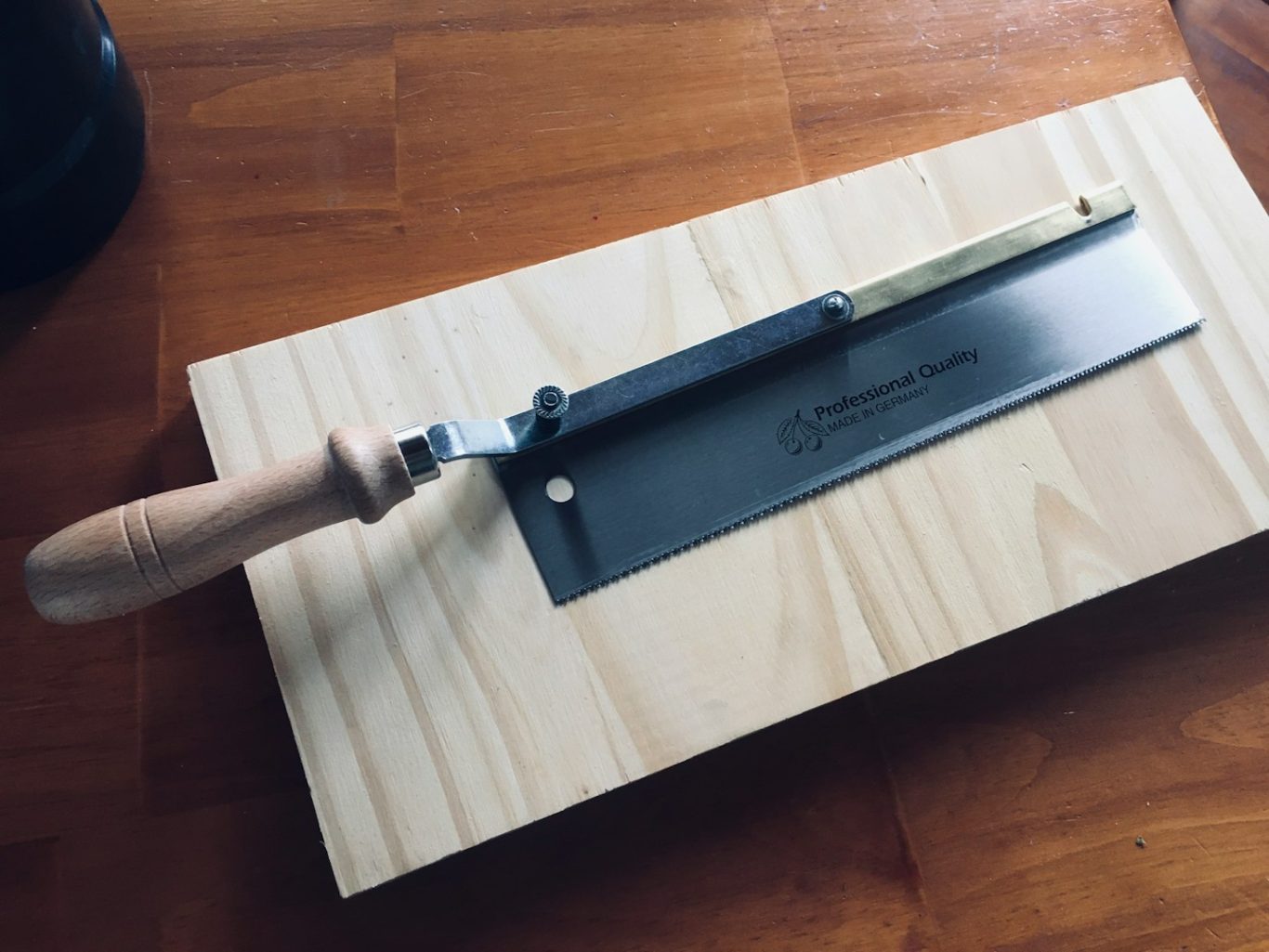 Holzarbeiten Schlichtes Sägenwerkzeug mit Holzgriff auf einer Holzoberfläche.